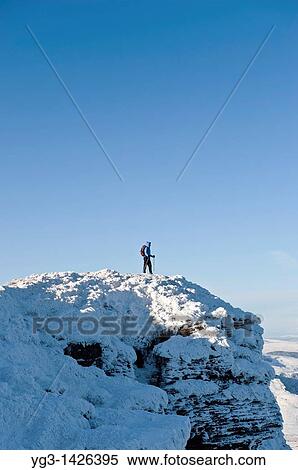 Stock Photography - Female hiker standing on summit of Corn Du in winter, Brecon Beacons national park, Wales. Fotosearch