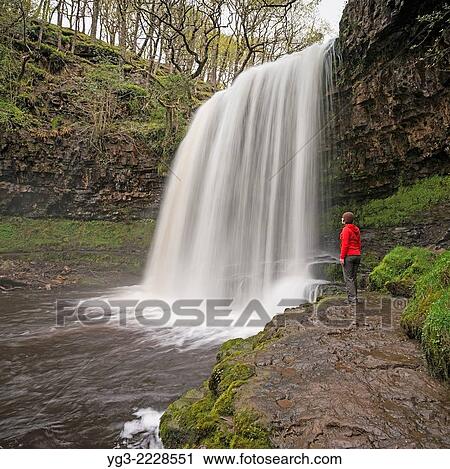 Female hiker stands near Sgwd yr Eira Waterfall - River Hepste, near Ystradfellte, Brecon Beacons national park, Wales. View Large Photo Image Stock Image - Female hiker stands near Sgwd yr Eira Waterfall - River Hepste, near Ystradfellte, Brecon Beacons national park, Wales.. Fotosearch