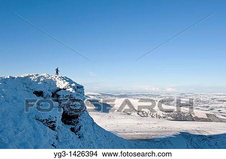 Picture - Female hiker stands on summit of Corn Du in winter, Brecon Beacons nationl park, Wales. Fotosearch