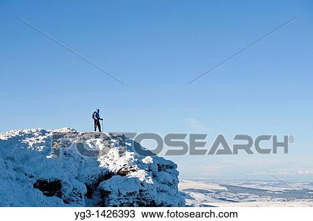 Stock Image - Female hiker stands on summit of Corn Du in winter, Brecon Beacons nationl park, Wales. Fotosearch