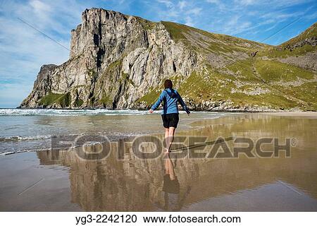 Female hiker walks in sea below Ryten at Kvalvika beach, Moskenesoy, Lofoten Islands, Norway. View Large Photo Image Stock Image - Female hiker walks in sea below Ryten at Kvalvika beach, Moskenesoy, Lofoten Islands, Norway.. Fotosearch