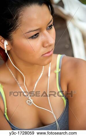 Stock Photo - Female hispanic teenager with earphones listening to music. Fotosearch