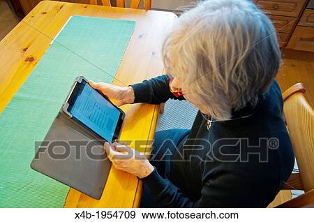 Stock Photo - Female in her early 70s using mini tablet Pori Finland Europe.. Fotosearch