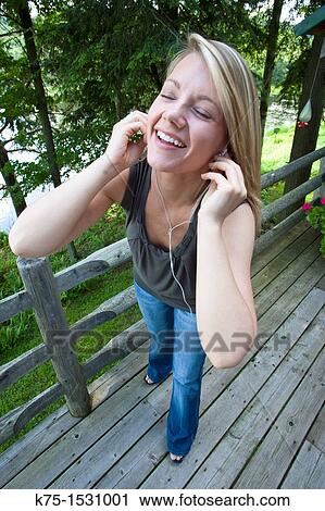 Stock Image - Female listening to music on her mp3 player. Fotosearch