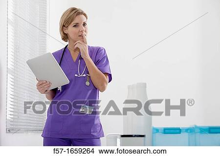 Female Nurse reviewing medical records on a tablet computer View Large Photo Image Picture - Female Nurse reviewing medical records on a tablet computer. Fotosearch