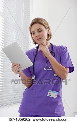 Female Nurse reviewing medical records on a tablet computer View Large Photo Image Stock Image - Female Nurse reviewing medical records on a tablet computer. Fotosearch