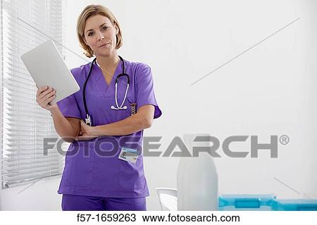 Female Nurse reviewing medical records on a tablet computer View Large Photo Image Stock Image - Female Nurse reviewing medical records on a tablet computer. Fotosearch