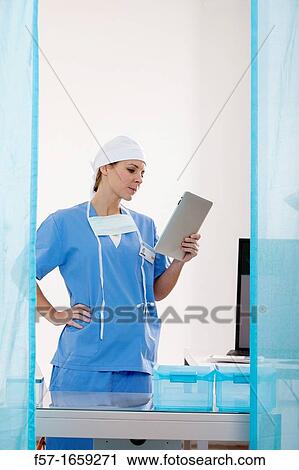 Stock Image - Female Nurse reviewing medical records on a tablet computer. Fotosearch