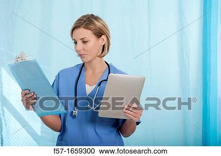 Female Nurse reviewing medical records on a tablet computer View Large Photo Image Stock Image - Female Nurse reviewing medical records on a tablet computer. Fotosearch