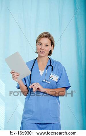 Female Nurse reviewing medical records on a tablet computer View Large Photo Image Stock Image - Female Nurse reviewing medical records on a tablet computer. Fotosearch