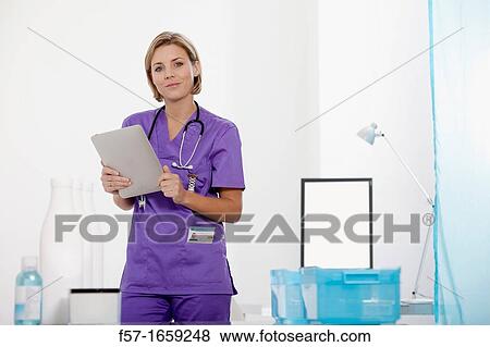 Stock Photo - Female Nurse reviewing medical records on a tablet computer. Fotosearch