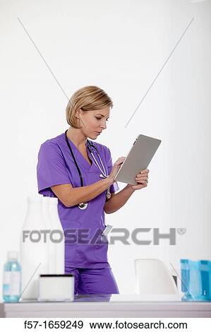 Female Nurse reviewing medical records on a tablet computer View Large Photo Image Stock Photo - Female Nurse reviewing medical records on a tablet computer. Fotosearch