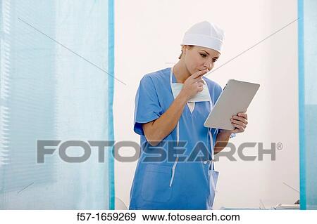 Female Nurse reviewing medical records on a tablet computer View Large Photo Image Stock Photo - Female Nurse reviewing medical records on a tablet computer. Fotosearch