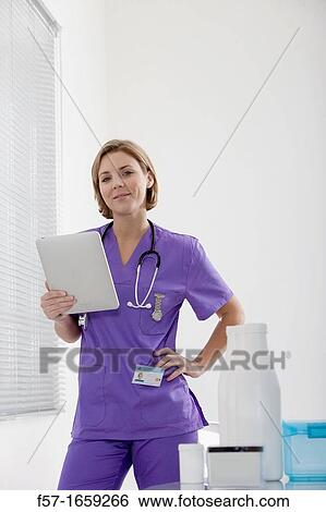 Female Nurse reviewing medical records on a tablet computer View Large Photo Image Stock Photograph - Female Nurse reviewing medical records on a tablet computer. Fotosearch