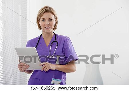 Stock Photography - Female Nurse reviewing medical records on a tablet computer. Fotosearch