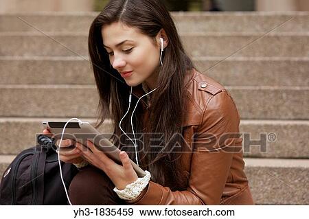 Stock Photo - Female student studying lecture from her ipad using iTunes U application. Fotosearch
