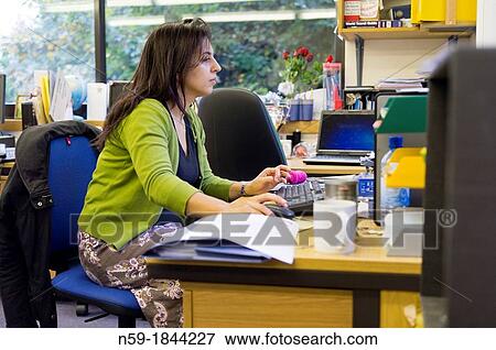 Stock Photo - Female teacher working at her desk in staffroom. Fotosearch