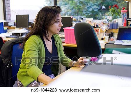 Stock Photo - Female teacher working at her desk in staffroom. Fotosearch