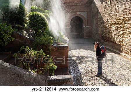 Female tourist cooling down from garden sprinkler in La Alhambra Palace grounds. Granada, Spain. View Large Photo Image Picture - Female tourist cooling down from garden sprinkler in La Alhambra Palace grounds. Granada, Spain.. Fotosearch