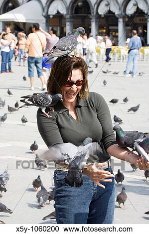 Stock Image - Female tourist feeding the pigeons at La Piazza di San Marco Venice Italy. Fotosearch
