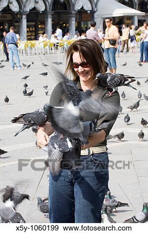 Stock Photo - Female tourist feeding the pigeons at La Piazza di San Marco Venice Italy. Fotosearch