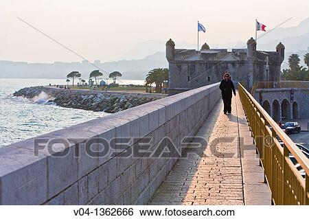 Female tourist walking towards the camera in front of the Citadelle in Menton, France, Europe View Large Photo Image Stock Photograph - Female tourist walking towards the camera in front of the Citadelle in Menton, France, Europe. Fotosearch