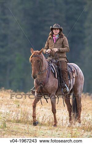Female wrangler cowgirl on horse 