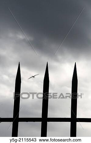 Stock Image - fence with spikes and dark sky. Fotosearch