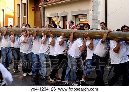 Stock Photograph - Fiesta de la Blanca Village men shoulder the bonfire to plant in the town plaza Nueva de Llanes Asturias. Fotosearch