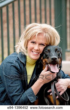 Fifty year old blond woman hugging a Doberman Pinscher on a stairway in a park. View Large Photo Image Stock Image - Fifty year old blond woman hugging a Doberman Pinscher on a stairway in a park.. Fotosearch