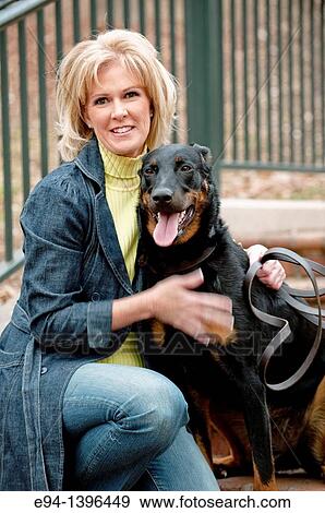Fifty year old blond woman hugging a Doberman Pinscher on a stairway in a park. View Large Photo Image Stock Photo - Fifty year old blond woman hugging a Doberman Pinscher on a stairway in a park.. Fotosearch