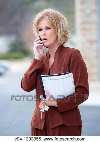 Fifty year old blond woman in business attire talking on a mobile phone View Large Photo Image Stock Photography - Fifty year old blond woman in business attire talking on a mobile phone. Fotosearch