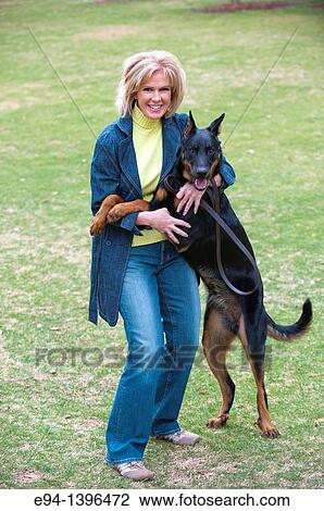 Fifty year old blond woman playing with a Doberman Pinscher in a park. View Large Photo Image Stock Image - Fifty year old blond woman playing with a Doberman Pinscher in a park.. Fotosearch