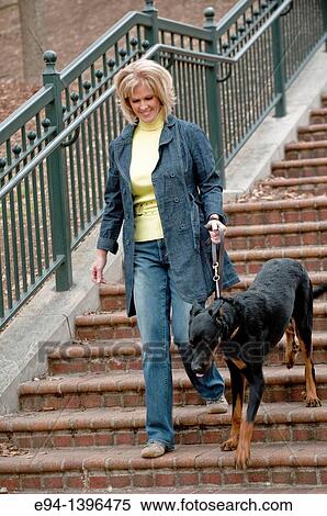 Fifty year old blond woman walking a Doberman Pinscher down a stairway in a park View Large Photo Image Stock Photography - Fifty year old blond woman walking a Doberman Pinscher down a stairway in a park. Fotosearch