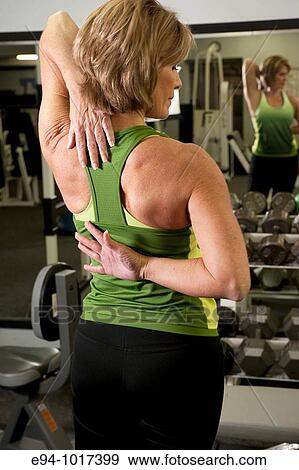 fifty year old blonde woman in a health club setting, back to camera, stretching arms behind her back View Large Photo Image Stock Photo - fifty year old blonde woman in a health club setting, back to camera, stretching arms behind her back. Fotosearch