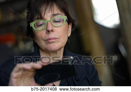 fifty years old lady looking at pictures on a mobile phone View Large Photo Image Stock Photo - fifty years old lady looking at pictures on a mobile phone. Fotosearch