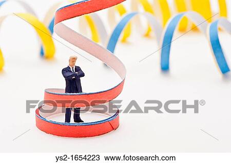 Stock Image - Figurine of businessman standing inside a streamer. Fotosearch