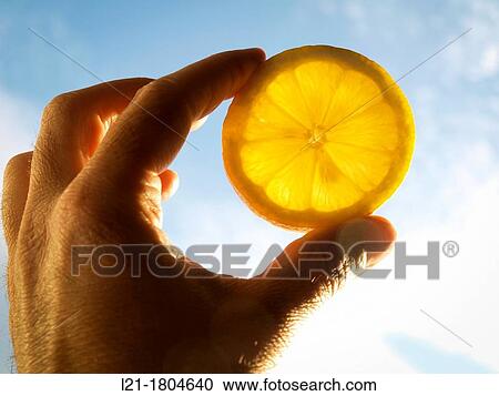 Fingers holding a lemon slice backlit. In the background: sky. View Large Photo Image Stock Image - Fingers holding a lemon slice backlit. In the background: sky.. Fotosearch