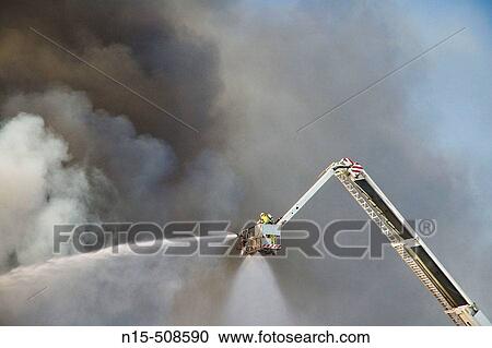Firefighter in crane sprays water on fire through clouds of black smoke. Perth, Western Australia. View Large Photo Image Stock Image - Firefighter in crane sprays water on fire through clouds of black smoke. Perth, Western Australia.. Fotosearch