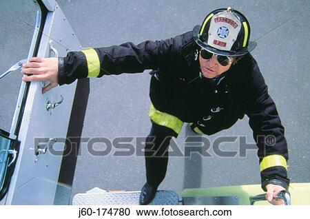 Stock Image - Fireman getting into firetruck. Fotosearch