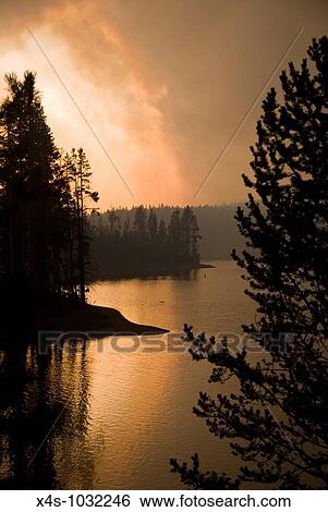 Stock Photograph - Firey colored clouds of smoke from a wildfire billow over Yellowstone Lake. Fotosearch