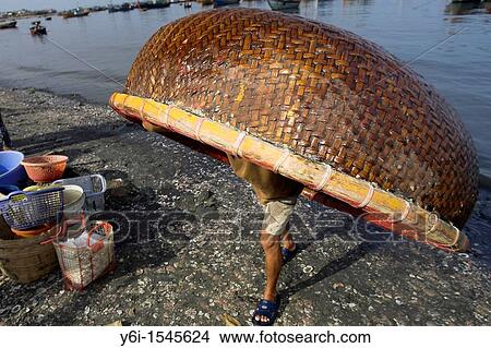 Fisherman carries small round woven boat on his back up beach Lang Chai fishing village near Mui Ne Vietnam View Large Photo Image Picture - Fisherman carries small round woven boat on his back up beach Lang Chai fishing village near Mui Ne Vietnam. Fotosearch