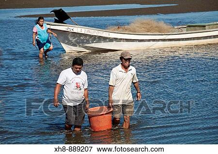 Stock Photo - Fishermen carry bucket with days catch, Poneloya beach, Leon, Nicaragua. Fotosearch