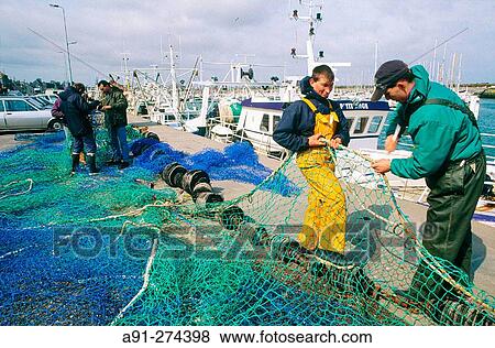 Fishermen mending nets on harbour quay. Granville. Manche. Normandy. France View Large Photo Image Stock Photo - Fishermen mending nets on harbour quay. Granville. Manche. Normandy. France. Fotosearch