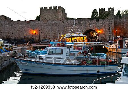 Stock Photo - Fishing boats and walls at the commercial port, City of Rhodes, Rhodes Island, Dodecanese, Greece, Mediterranean Sea.. Fotosearch