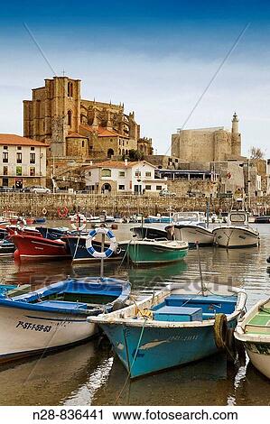 Stock Image - Fishing boats at port and Santa Maria de la Asuncion and castle in background, Castro Urdiales, Cantabria, Spain. Fotosearch