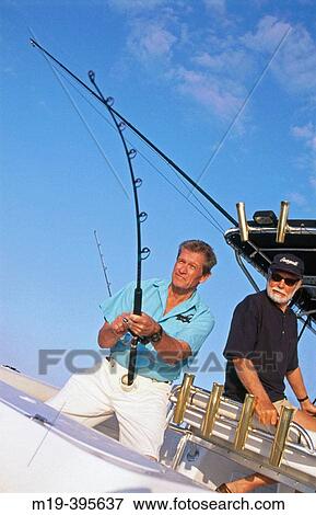 Stock Photo - fishing buddies deep sea fishing on a boat. Fotosearch