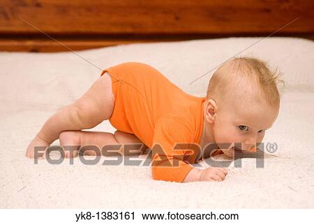 Stock Image - Five month old baby crawling on bed. Fotosearch