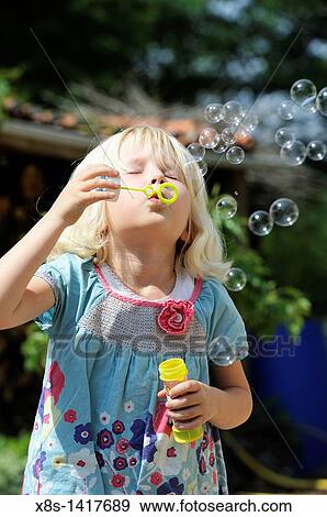 Stock Photo - Five year old girl blowing bubbles. Fotosearch