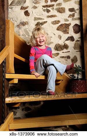 Stock Photograph - Five year old girl sitting on the staircase smiling. Fotosearch